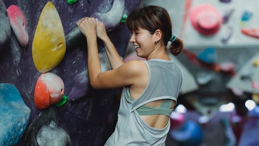 positive ethnic climber climbing on grips during boulder training